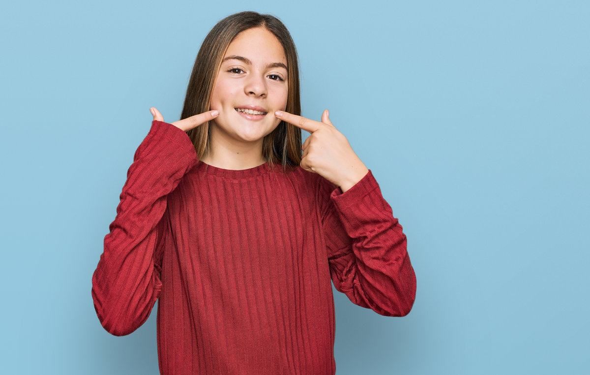 Beautiful brunette little girl wearing casual sweater smiling cheerful showing and pointing with fingers teeth and mouth. dental health concept.