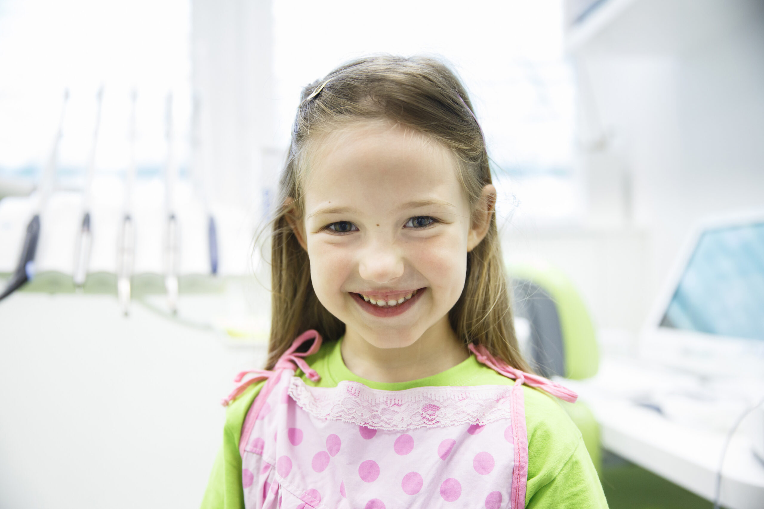 Relaxed little girl at dental office, smiling and waiting for a checkup. Early prevention, paedodontics and no fear concept.