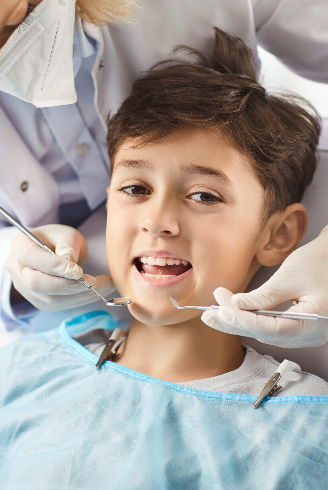 Dentist in the clinic examines a smiling boy, close-up. At the doctor, the child opened his mouth to examine his teeth. Concept dental health in adolescents, dental hygiene , tooth decay
