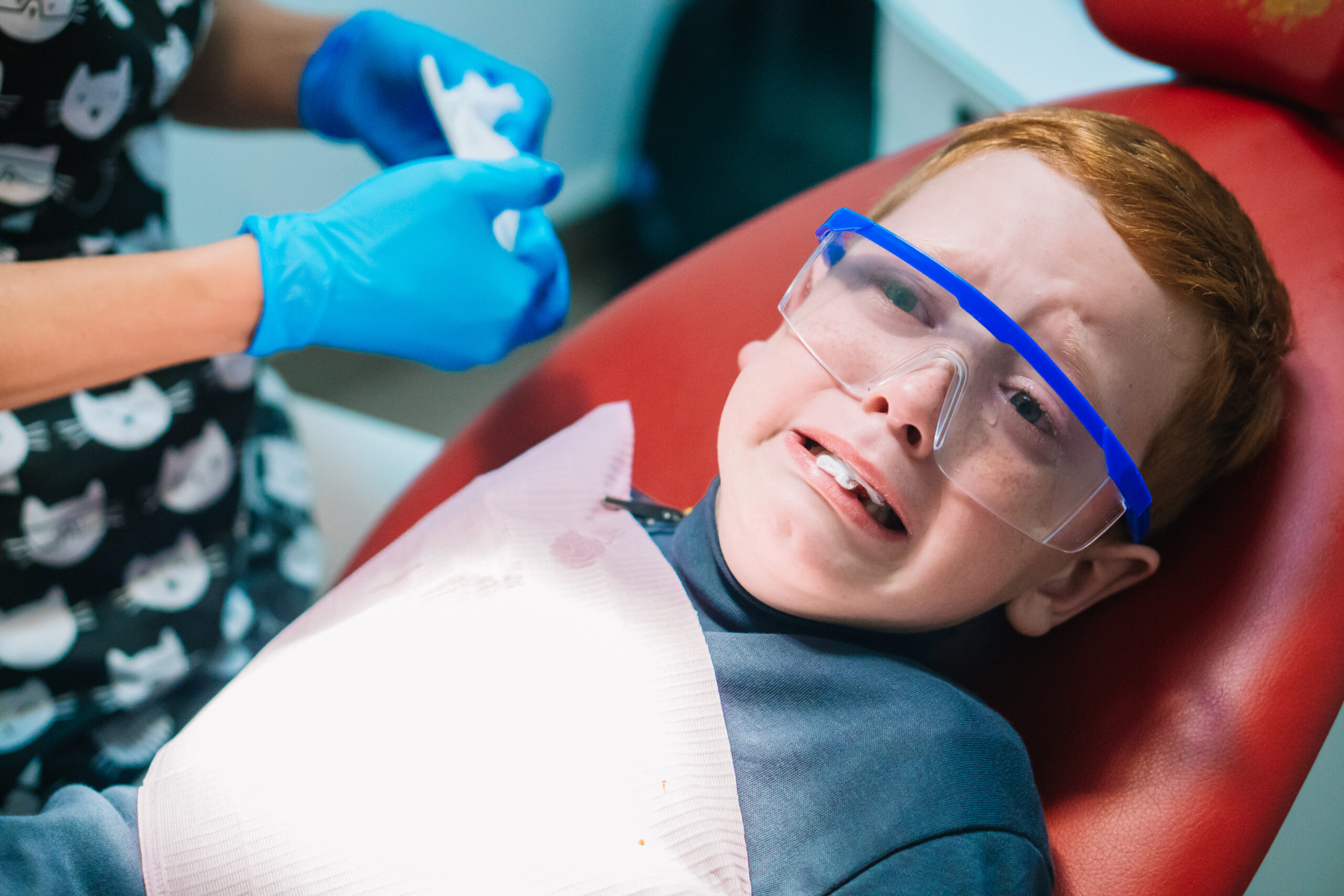 Scared red-haired boy crying at reception at dentist in dental chair. Pediatric dentistry