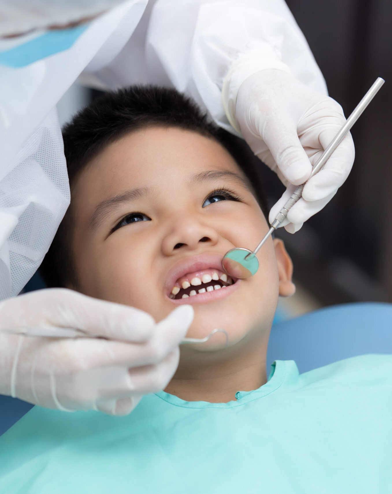 Dentist examining Asian little boy teeth in clinic.