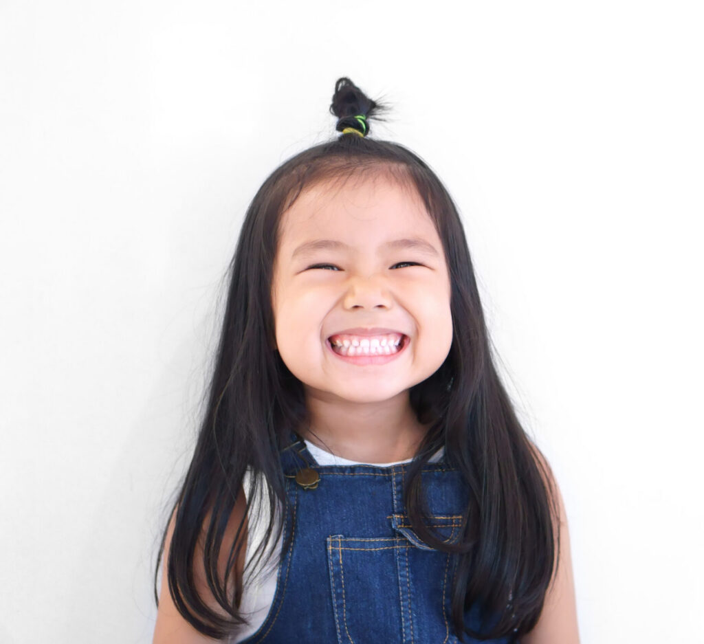 Asian children cute or kid girl and kindergarten student happy smile white teeth and laugh with wear dungarees jean for fashion on white background with space isolated