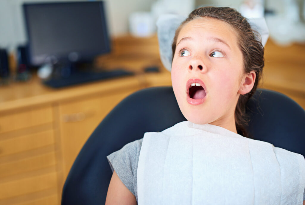 Dental, wow or scared girl in consultation room with phobia, worry or fear for dentist exam. Orthodontics, stress or teen person nervous for teeth, cavity or bacteria, risk or gum disease emergency.